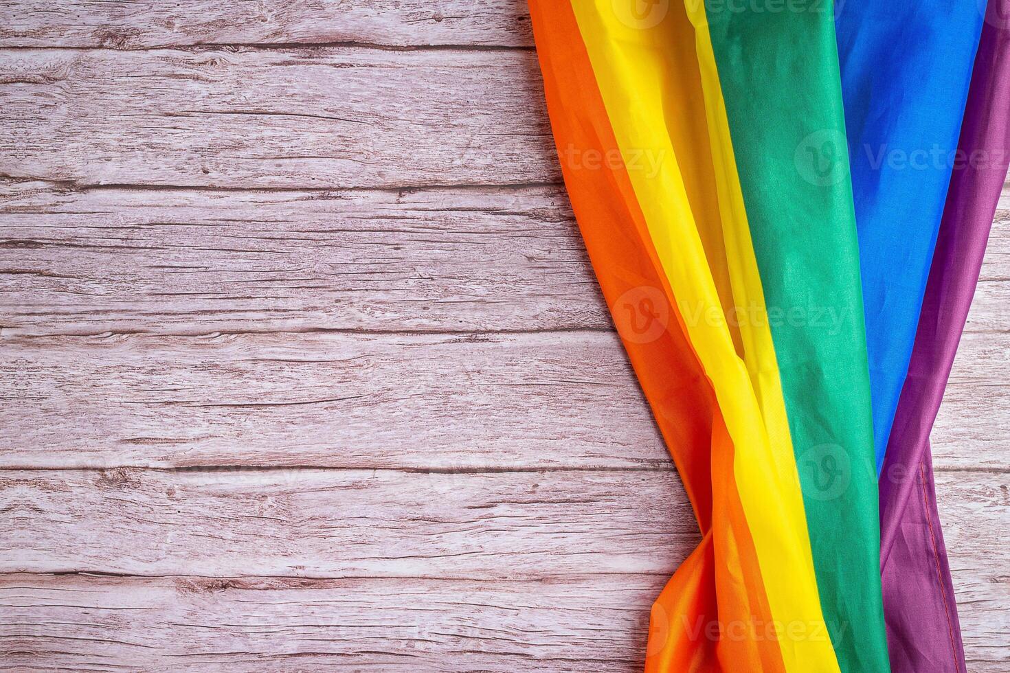 Close-up of LGBT flag on wooden table. Space for text photo