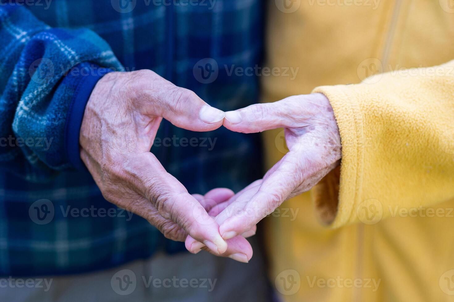 Close-up of the elderly couple showing making a heart with fingers. Concept of aged people and love photo