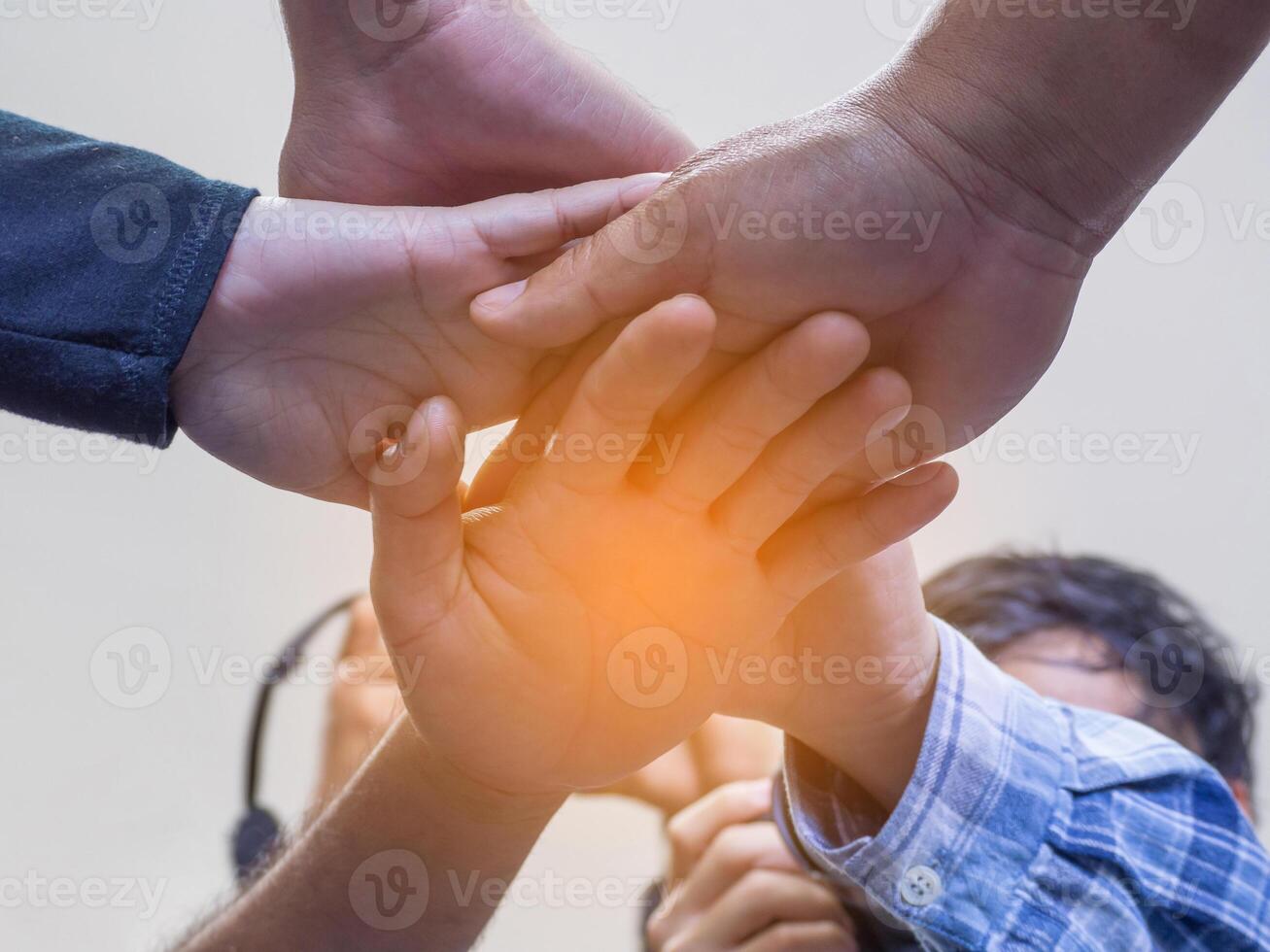 A low view of many people's hands in a circle together with sunlight effect. Concept of unity and together photo