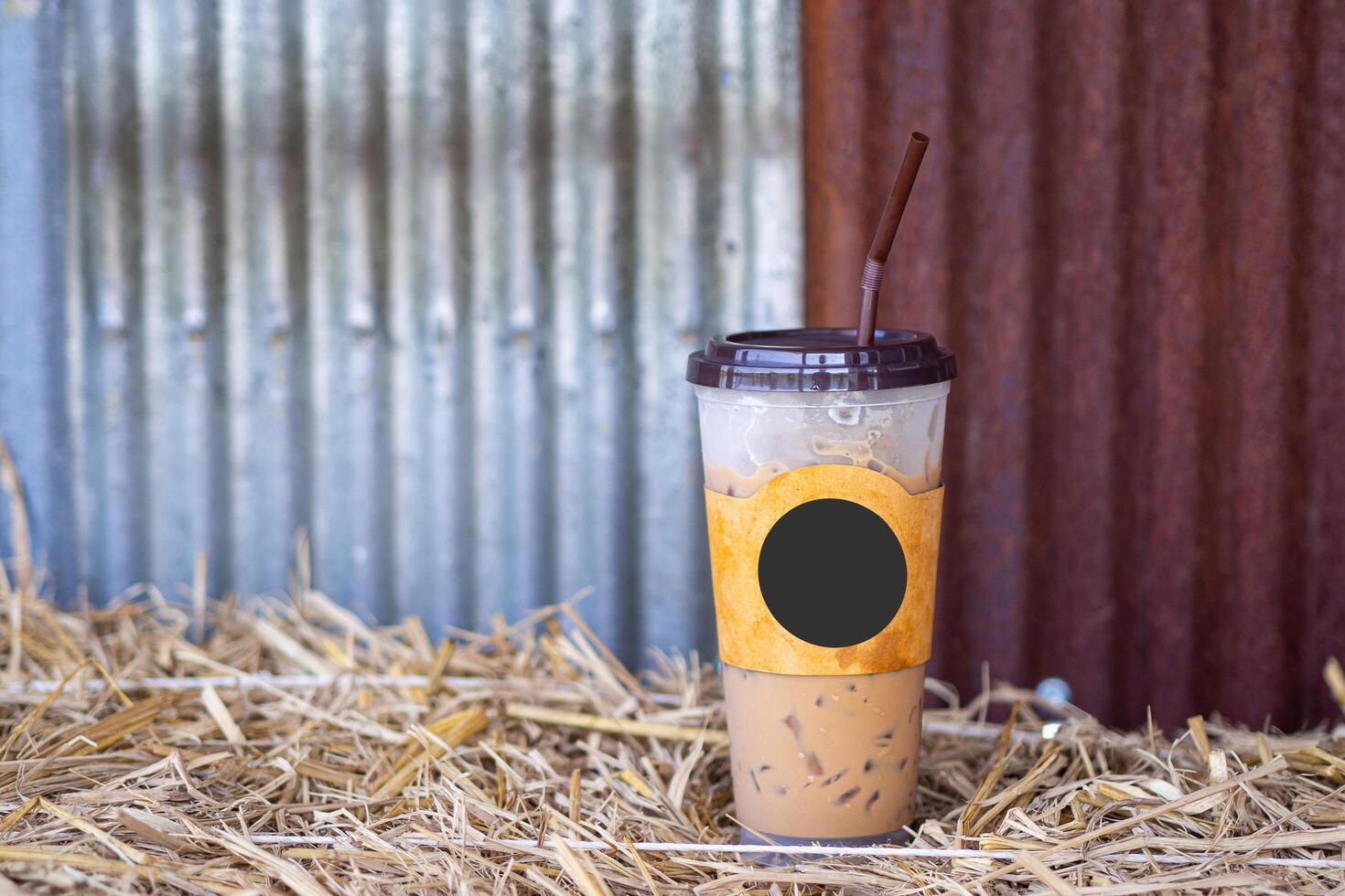 Iced coffee cup placed on a straw with a galvanized wall in the cafe shop. Space for text photo