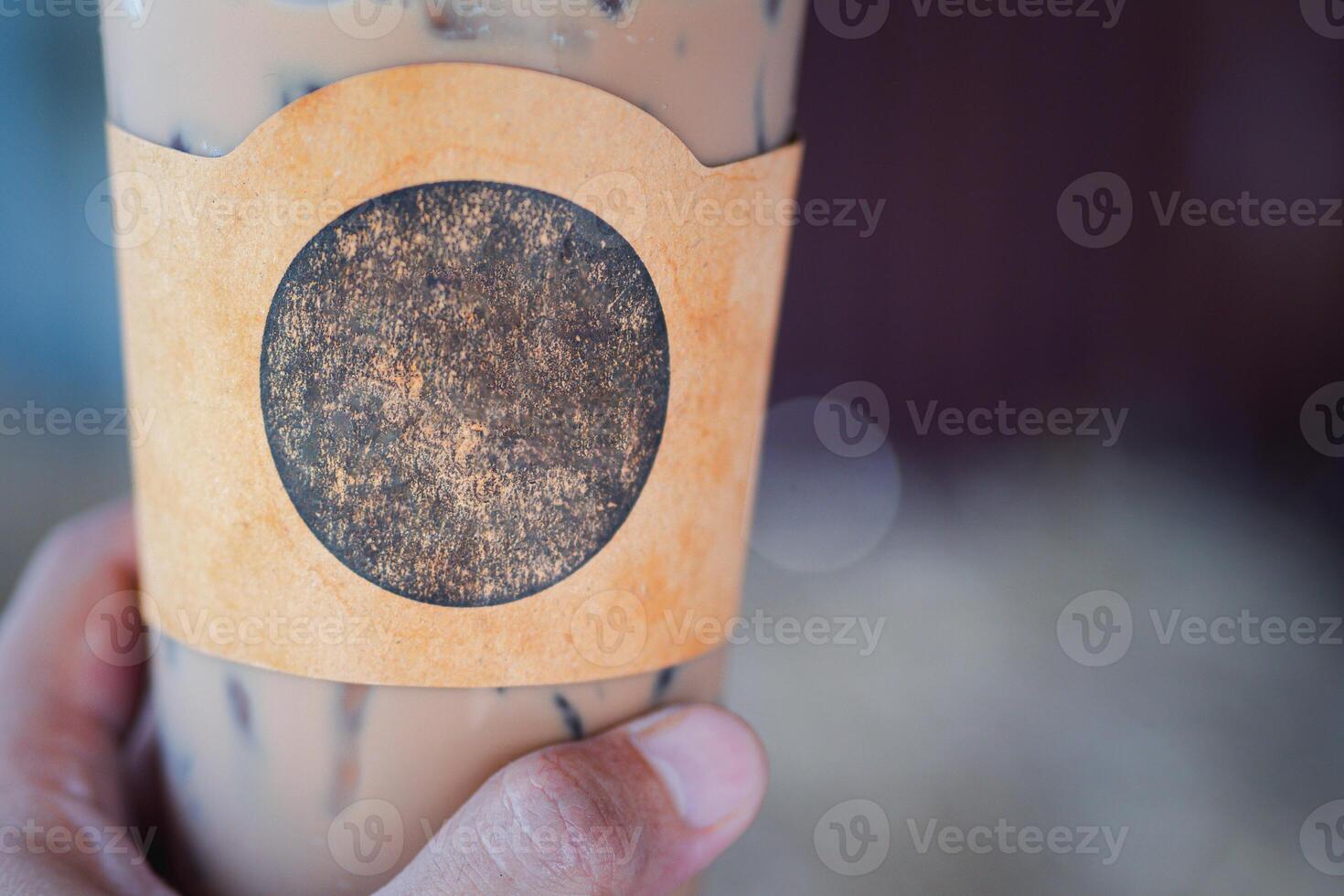 Close-up of an iced coffee cup in a woman's hand in the cafe shop. Space for text photo