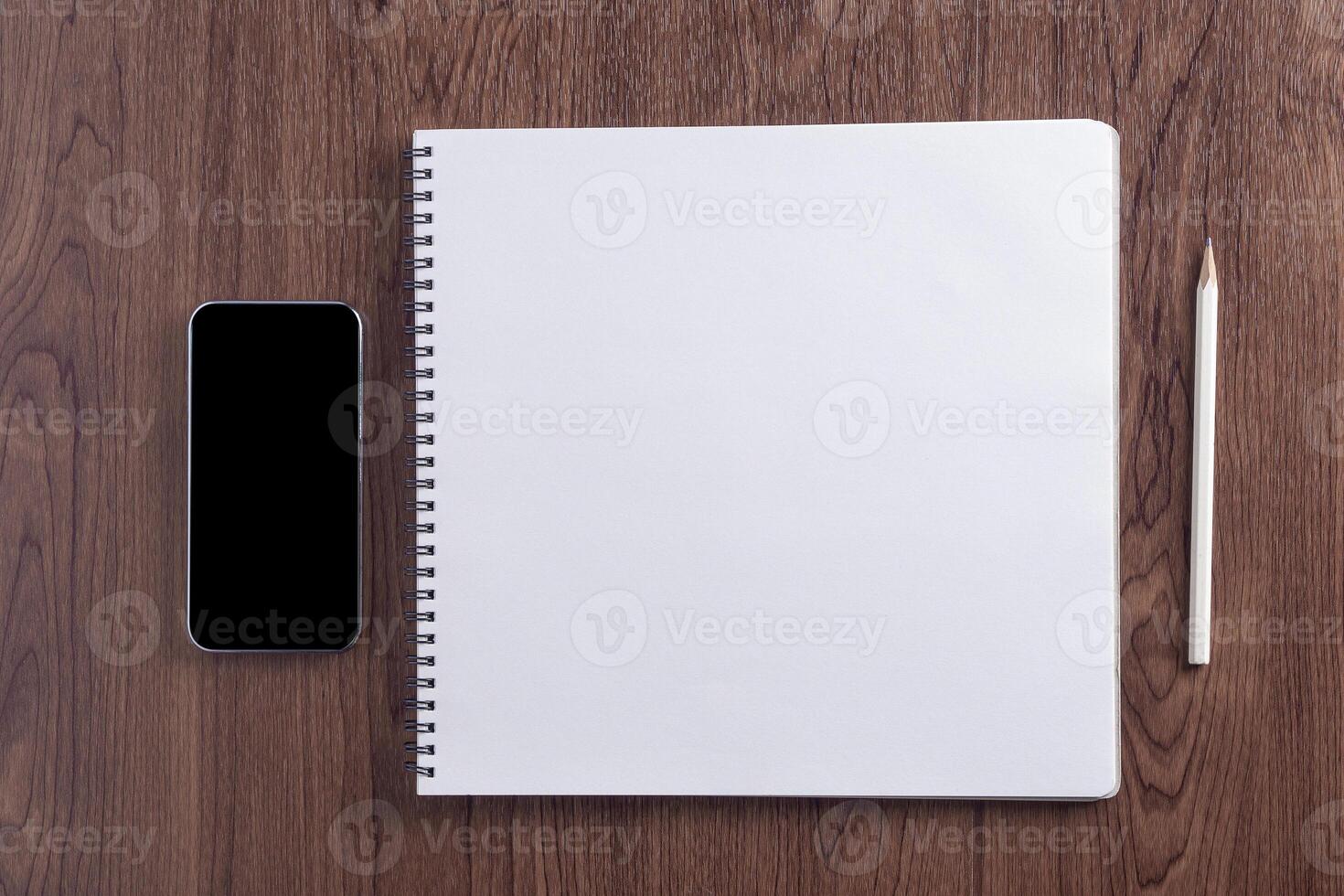 Top view of a desk with a tablet, pencil, glasses, a cup of coffee, and croissant on a plate placed on a wooden table. Work from home. Space for text photo