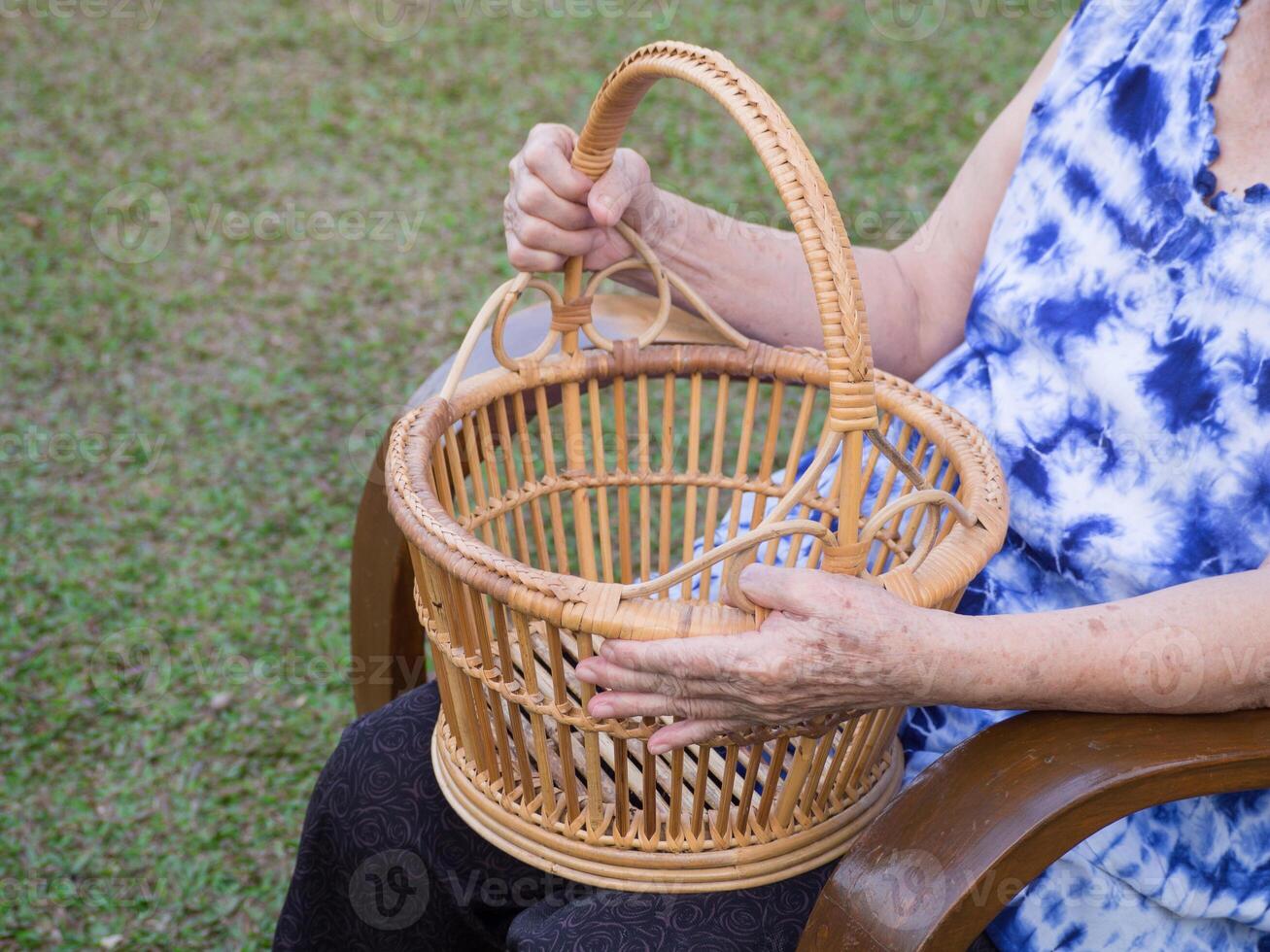 Hands of a senior woman holding a basket while sitting on a chair in a garden. Space for text. Concept of aged people and relaxation photo