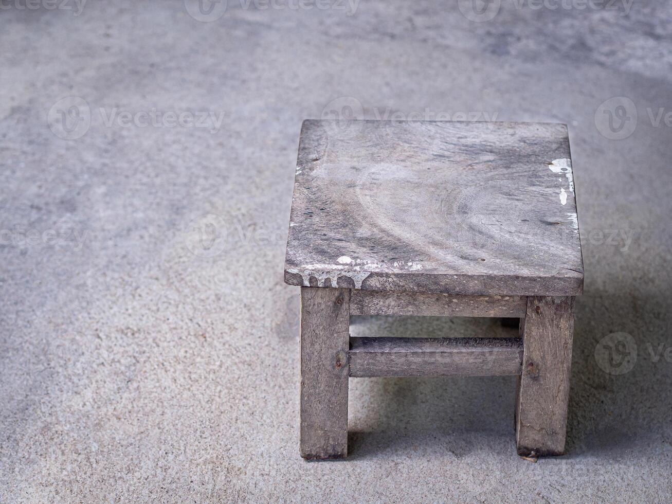Close-up of vintage wooden stool on a concrete floor. Space for text photo