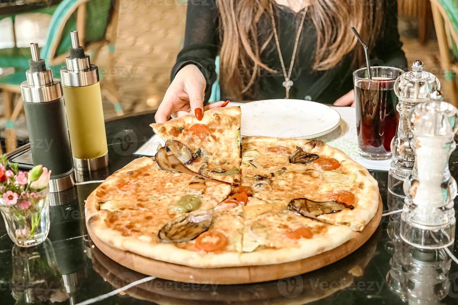 Woman Sitting at Table Enjoying a Large Pizza photo