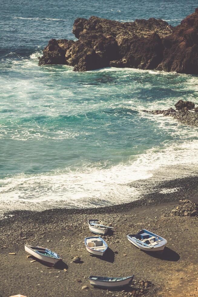 atlántico Oceano en el isla de lanzarote un maravilloso rocoso playa con pescar barcos rodeado por volcánico montañas el golfo bahía en el atlántico océano. lanzarote canario islas foto