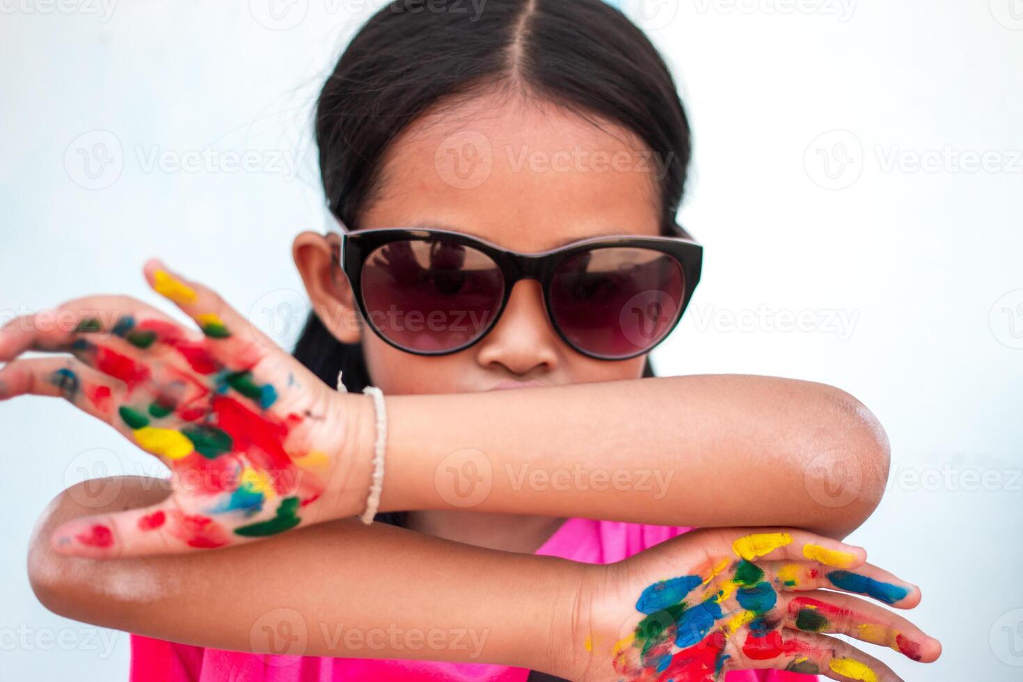 Cute little girl with colorful painted hands on wall background photo