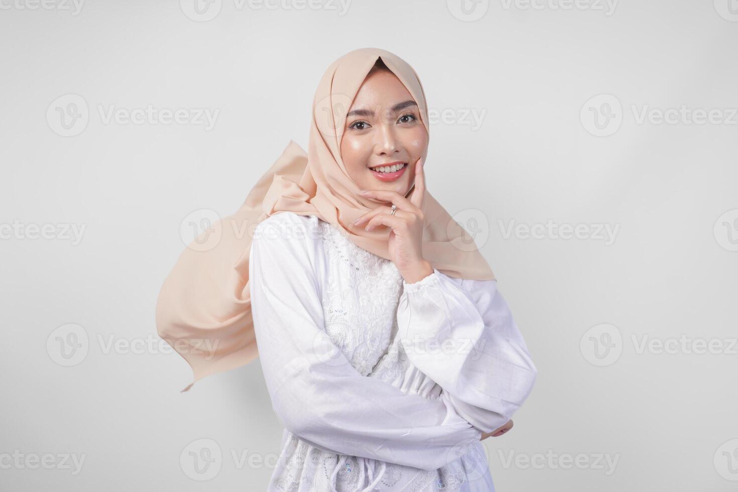 Elegant young Asian Muslim woman wearing white dress with hijab waving in the wind, modelling pose on white background photo