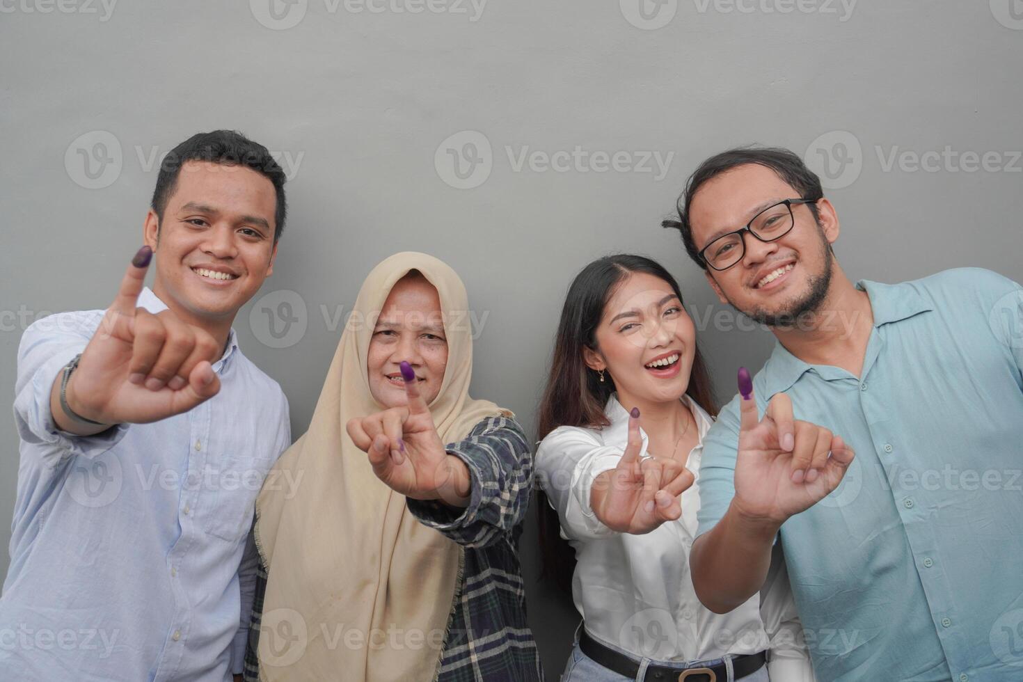 retrato de emocionado indonesio familia demostración el pequeño dedo sumergido en púrpura tinta después votación para general elección o pemilu para presidente y gobierno, aislado gris antecedentes foto