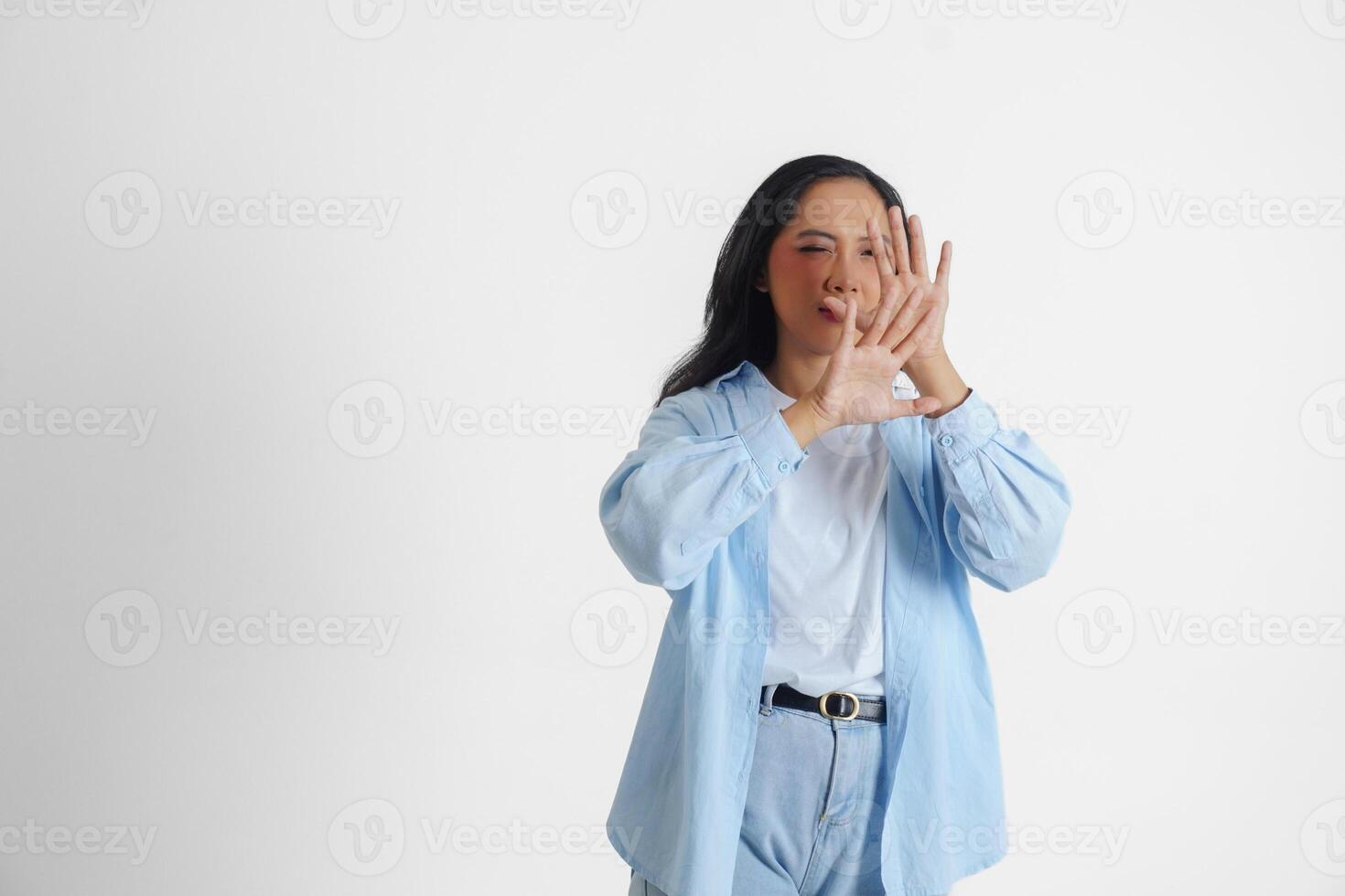 Asian woman wearing casual blue shirt is gesturing frightened gesture with hands and covering her face, isolated white background photo