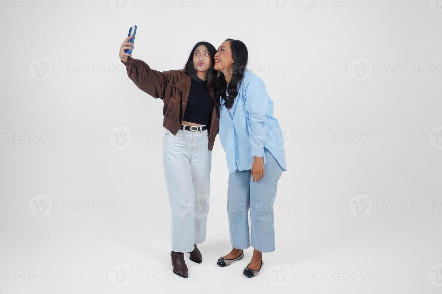 Female friends laughing and taking a fun selfie isolated by white background photo
