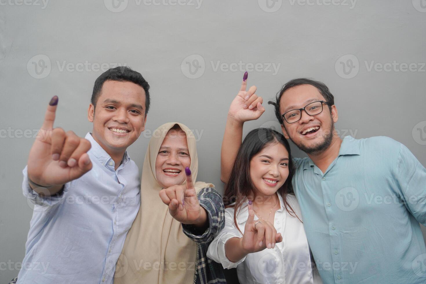 retrato de emocionado indonesio familia demostración el pequeño dedo sumergido en púrpura tinta después votación para general elección o pemilu para presidente y gobierno, aislado gris antecedentes foto