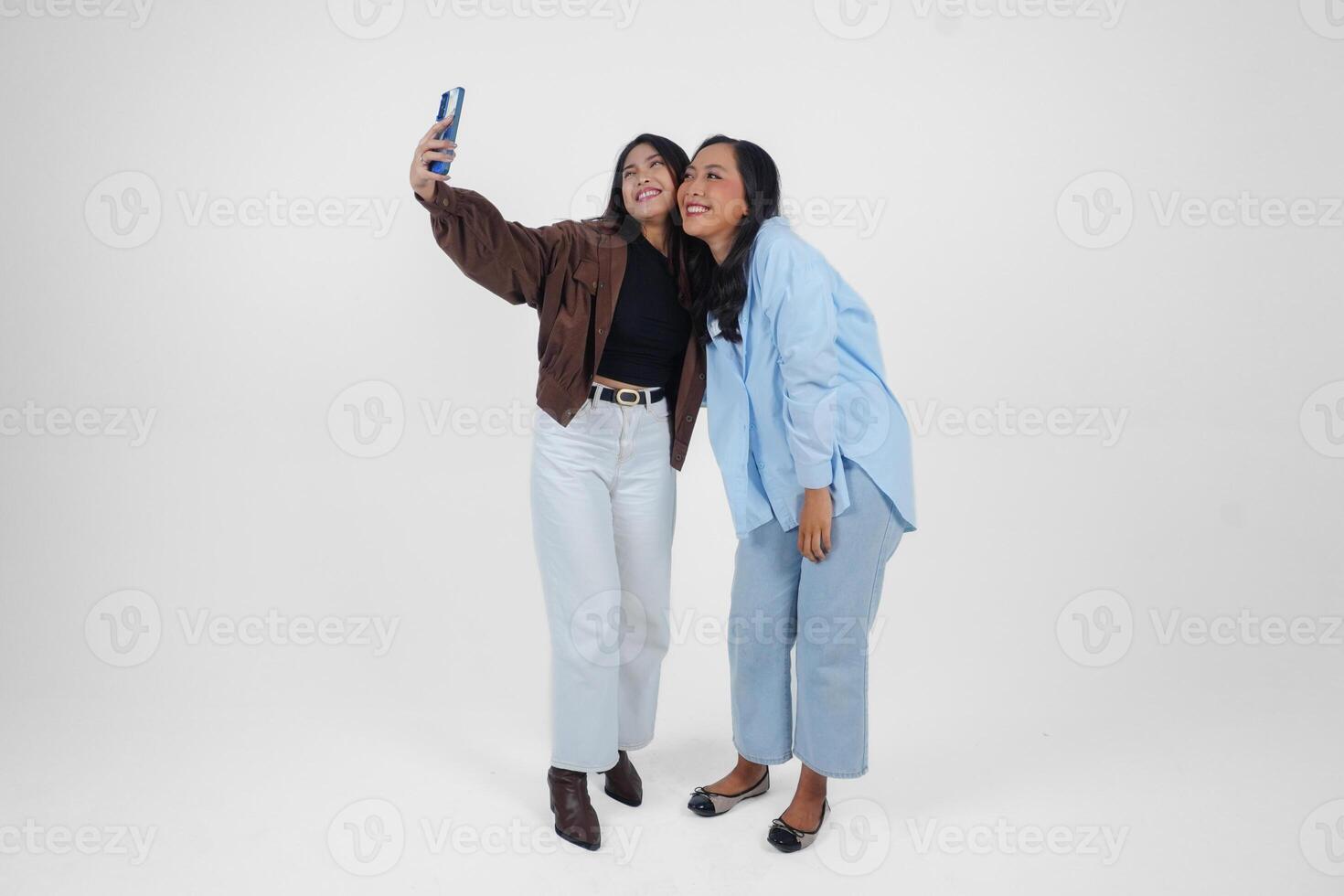 hembra amigos riendo y tomando un divertido selfie aislado por blanco antecedentes foto