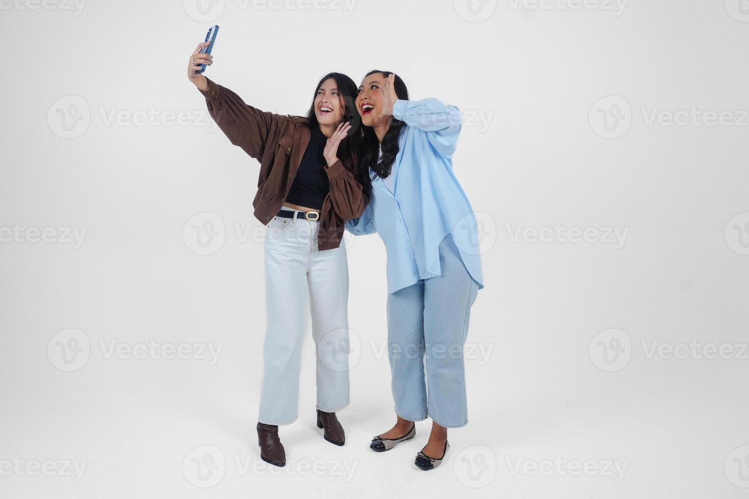 Female friends laughing and taking a fun selfie isolated by white background photo