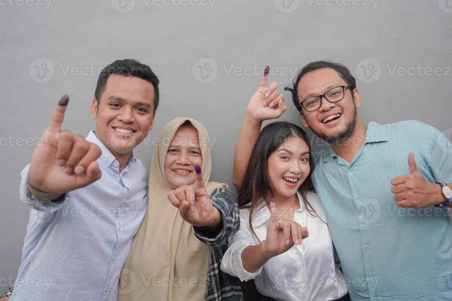 retrato de emocionado indonesio familia demostración el pequeño dedo sumergido en púrpura tinta después votación para general elección o pemilu para presidente y gobierno, aislado gris antecedentes foto