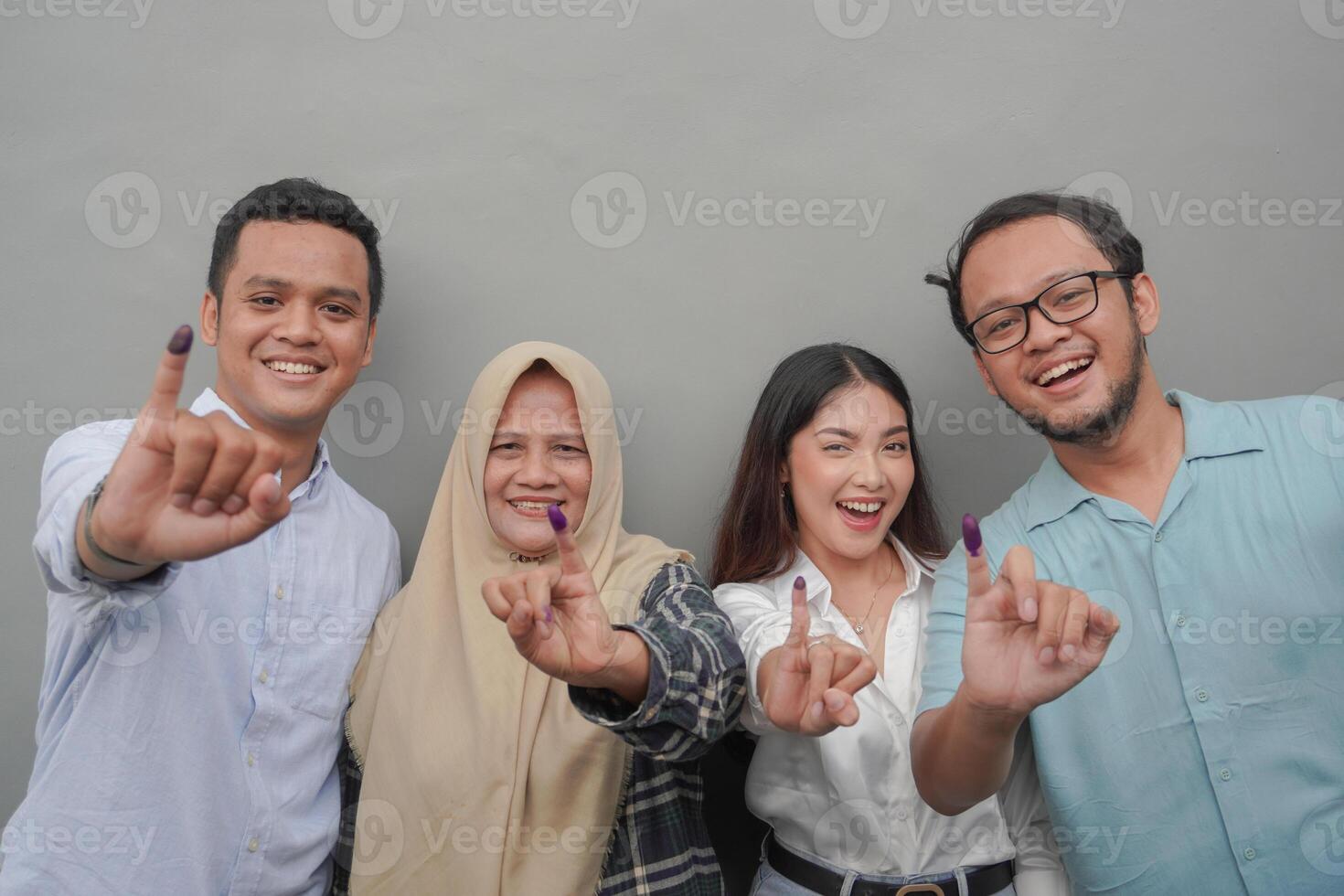 retrato de emocionado indonesio familia demostración el pequeño dedo sumergido en púrpura tinta después votación para general elección o pemilu para presidente y gobierno, aislado gris antecedentes foto