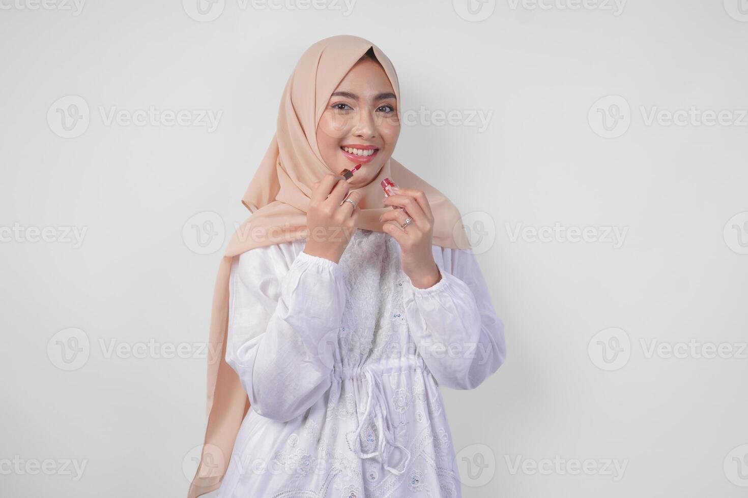 hermosa joven asiático musulmán mujer vistiendo blanco vestir y hijab poniendo en maquillaje aplicando lápiz labial. Moda y productos cosméticos belleza concepto foto
