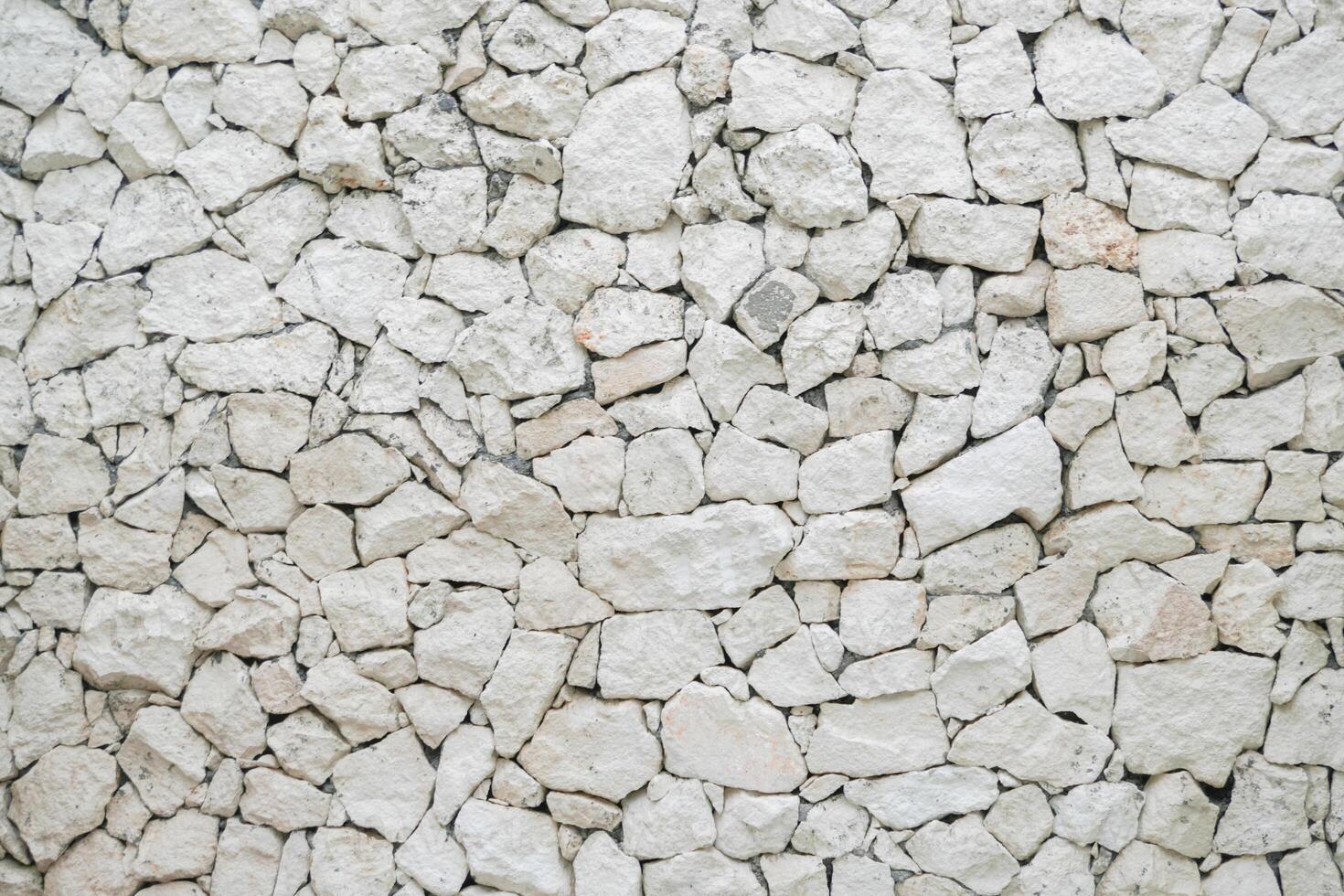 Decorative uneven cracked pattern of real stone wall surface with light pastel color and modern style. Interior and architecture concept photo