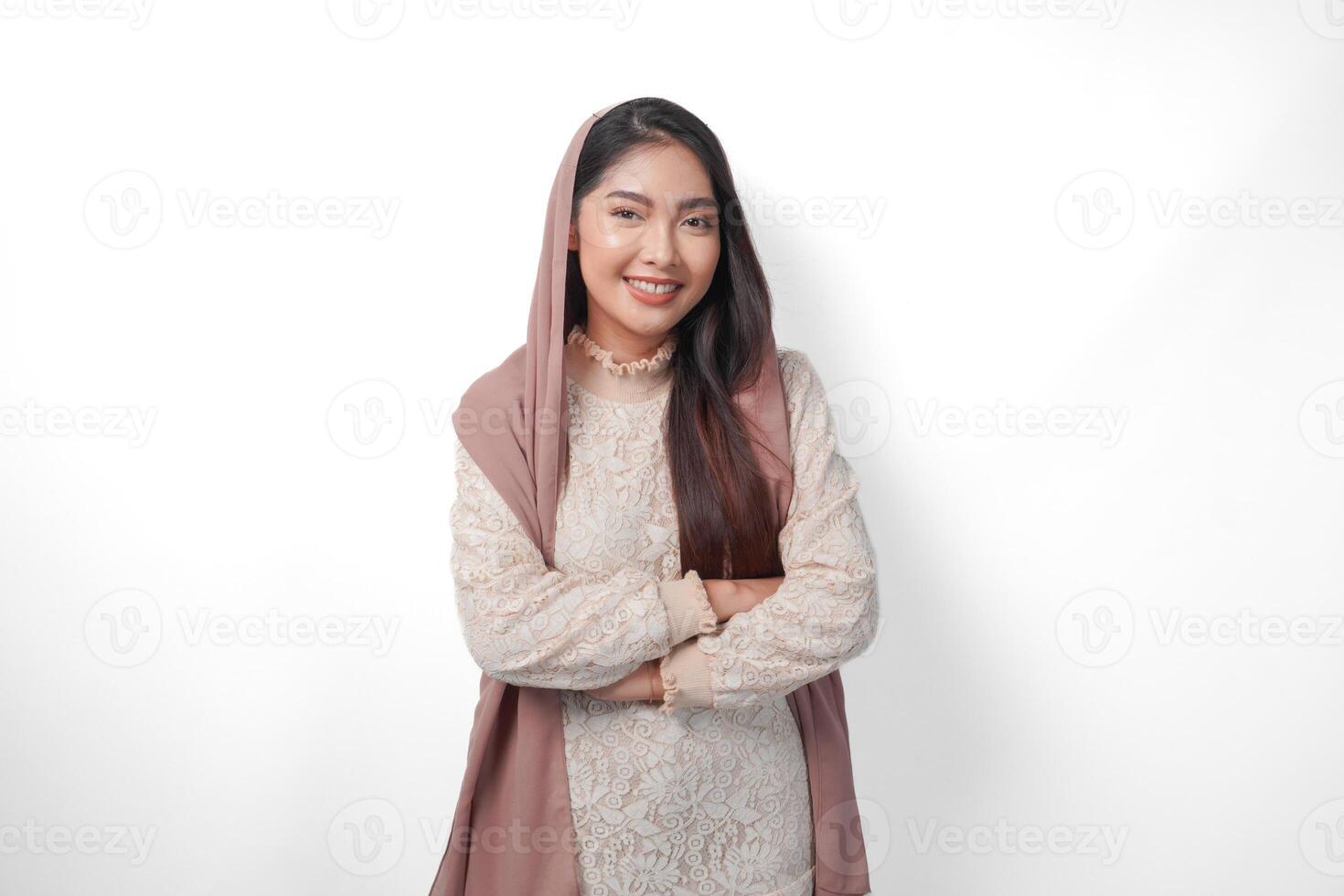 joven asiático musulmán mujer vistiendo Pañuelo velo sonriente a el cámara con cruzado brazos actitud lleno de confianza, aislado por blanco antecedentes foto