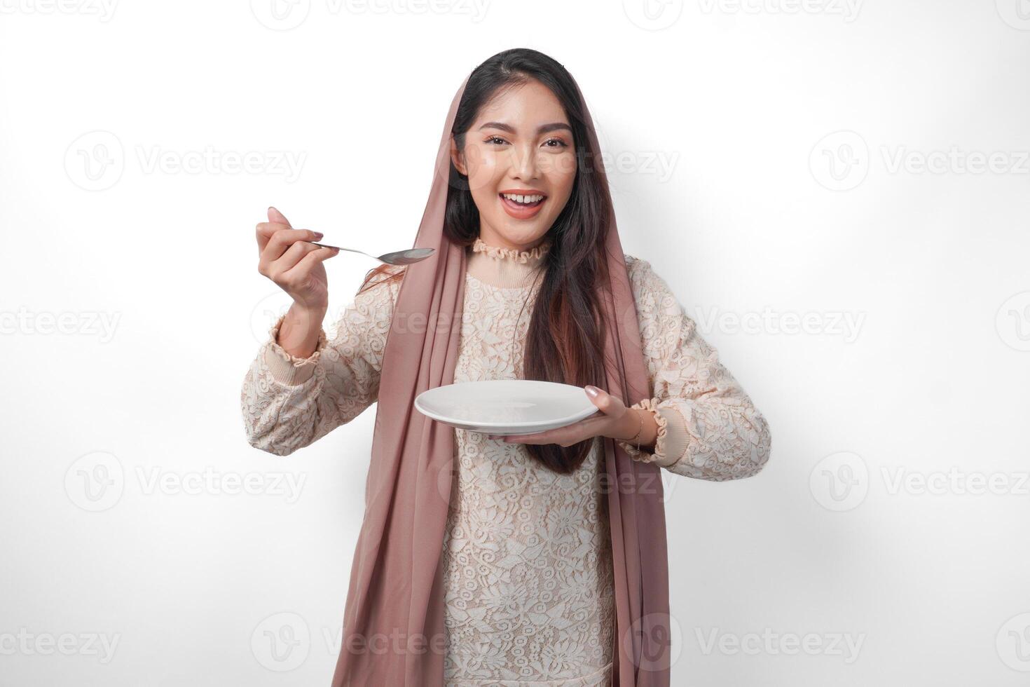 retrato de hambriento asiático musulmán mujer participación cuchillería y plato con Copiar espacio, sensación emocionado a comer después rápido en aislado blanco antecedentes. Ramadán concepto foto