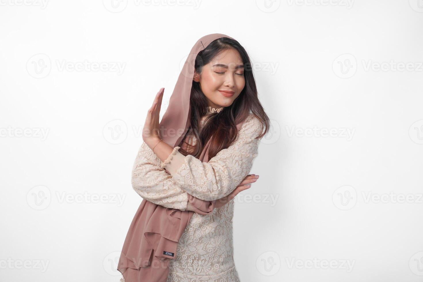 Young Asian Muslim woman wearing veil hijab gesturing a no rejection, refuse using hands and fingers, isolated by white background. Ramadan and Eid Mubarak concept photo
