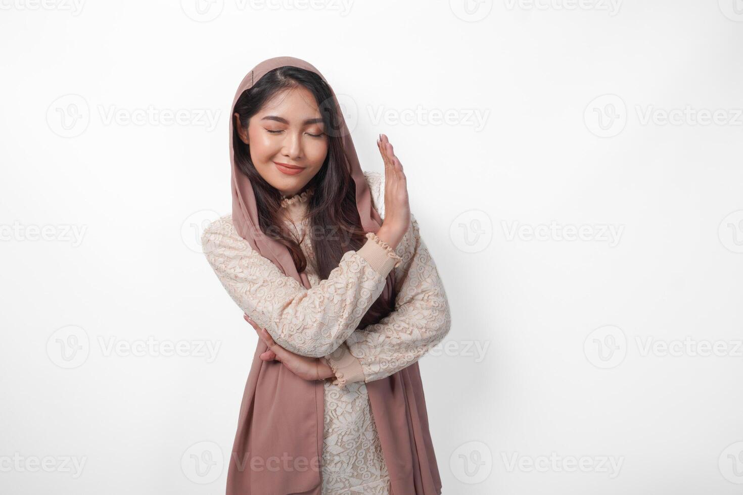 Young Asian Muslim woman wearing veil hijab gesturing a no rejection, refuse using hands and fingers, isolated by white background. Ramadan and Eid Mubarak concept photo