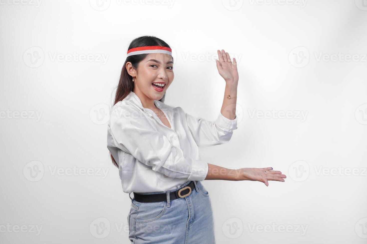 Excited Asian woman wearing flag headband presenting and pointing at the copy space on the side, smiling wide and standing on isolated white background. Independence day advertisement concept photo