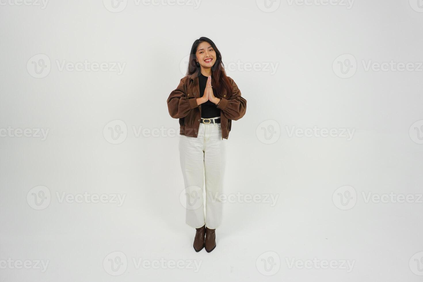 un lleno cuerpo retrato de asiático joven mujer con casual atuendo haciendo saludo gesto con dos manos mientras sonriente, en pie en aislado blanco antecedentes foto
