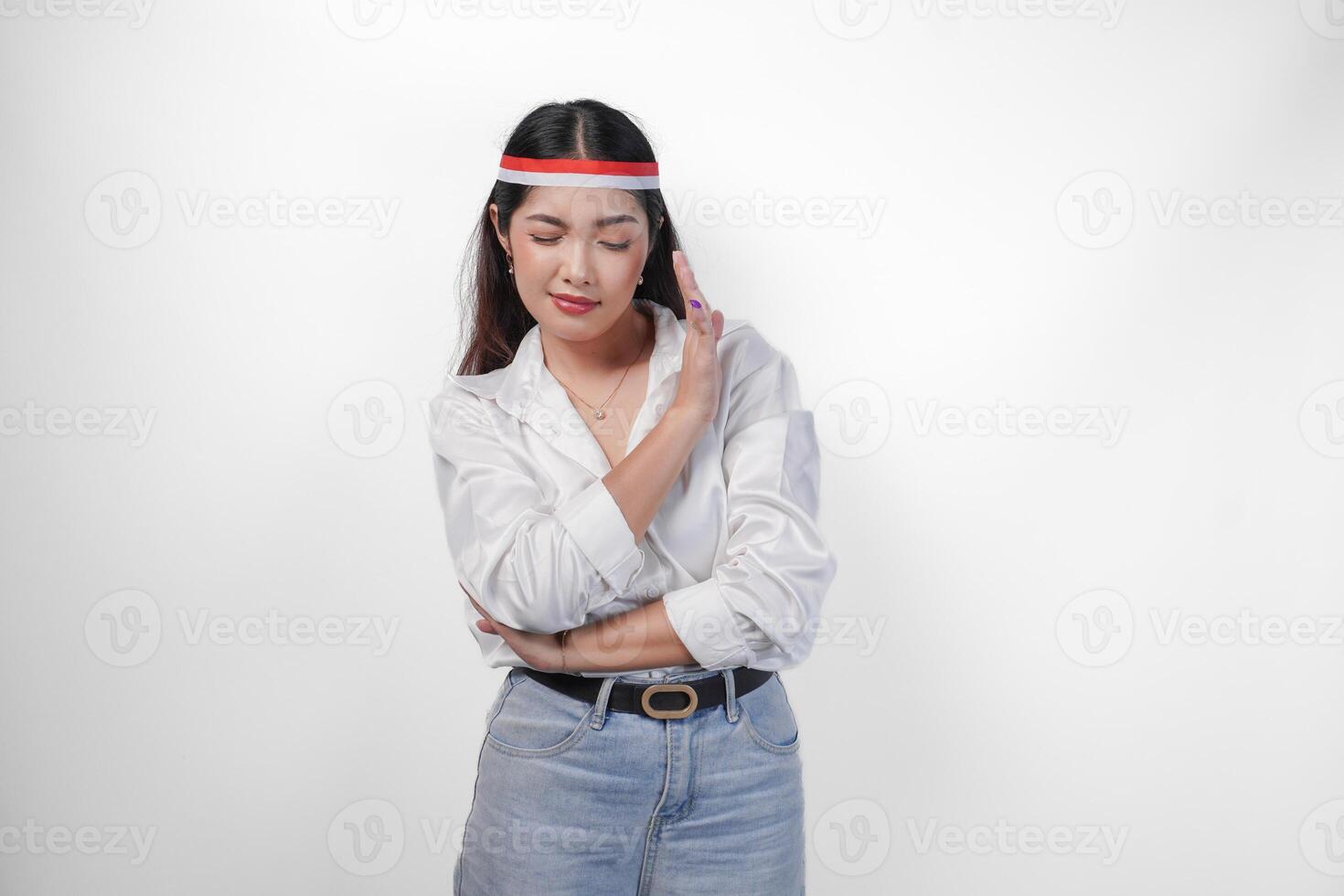 Young Asian woman wearing casual outfit and flag headband showing palm as a refusal and rejection sign, saying no, asking to stop, standing over isolated white background photo