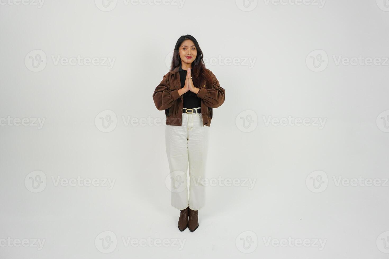 A full body portrait of Asian young woman with casual outfit making greeting gesture with two hands while smiling, standing on isolated white background photo