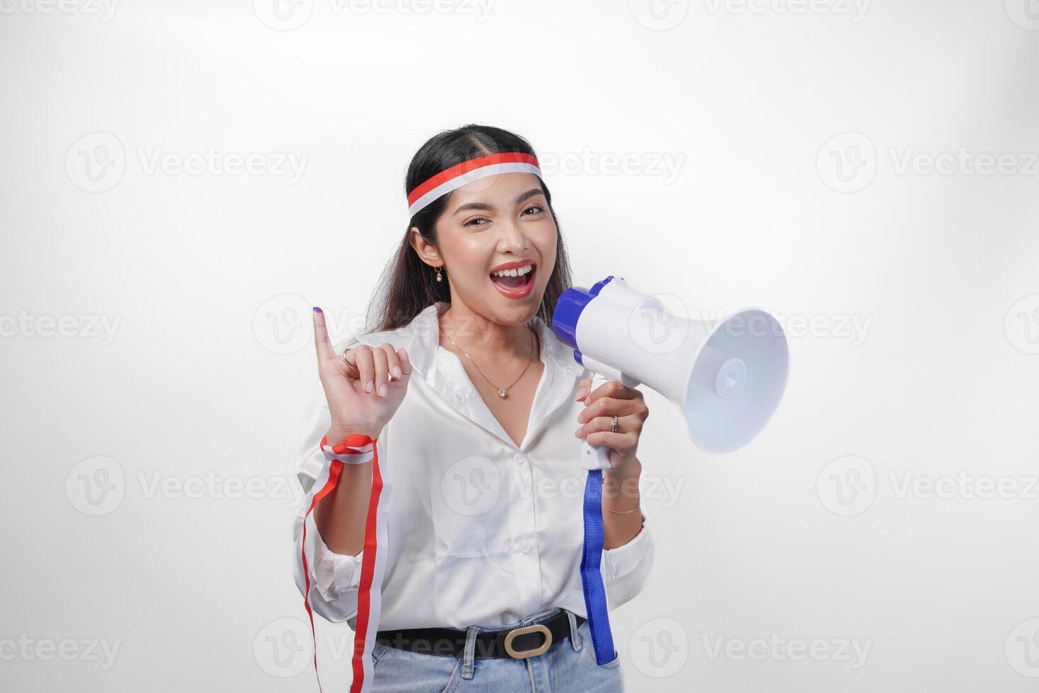 energético indonesio mujer en casual formal atuendo vistiendo país bandera venda mientras participación y gritos a megáfono, con orgullo demostración pequeño dedo sumergido en púrpura tinta después votación para elección foto