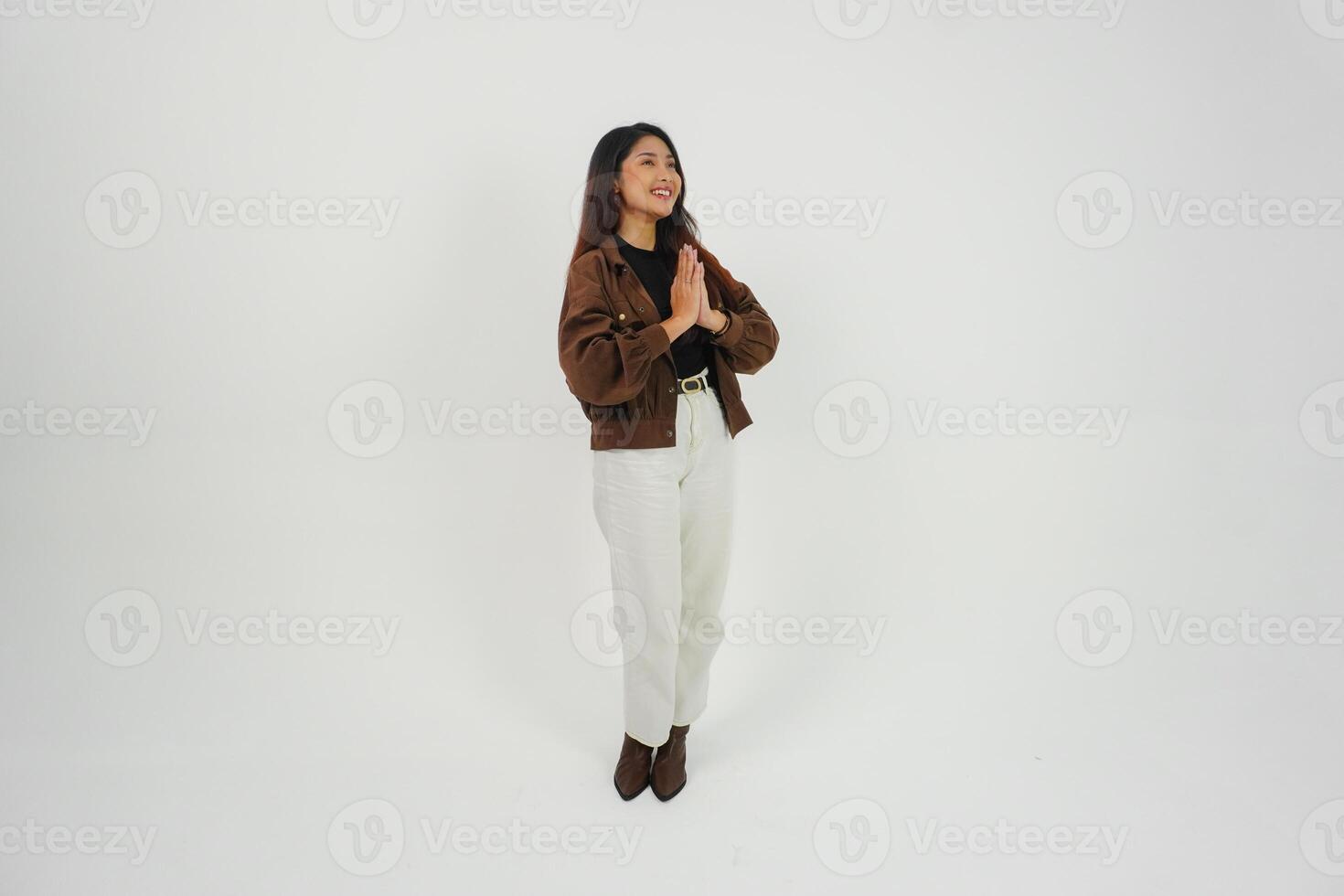 un lleno cuerpo retrato de asiático joven mujer con casual atuendo haciendo saludo gesto con dos manos mientras sonriente, en pie en aislado blanco antecedentes foto