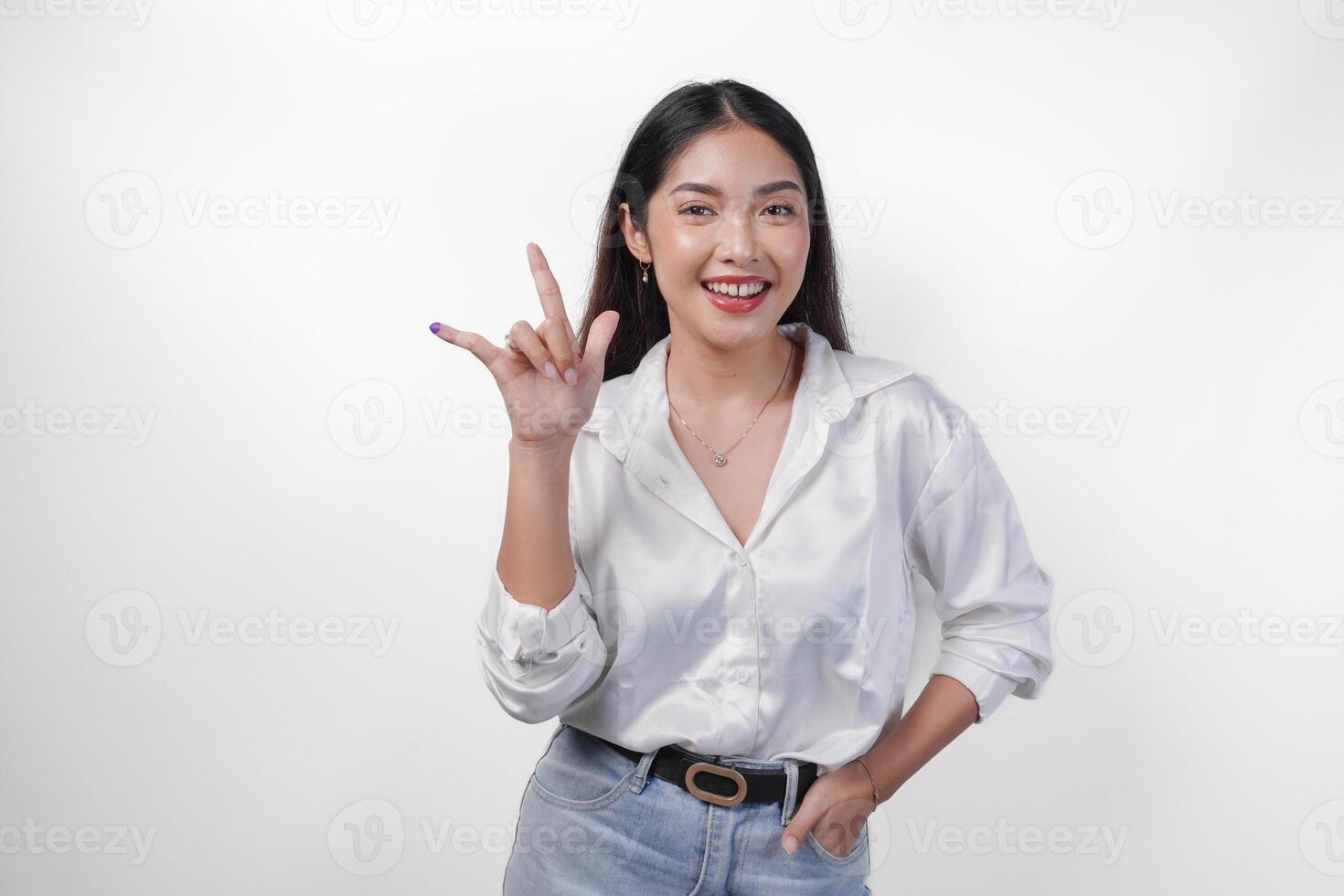 Excited Asian young woman showing little finger dipped in purple ink after voting for Pemilu or Indonesia election and pointing with fingers number one two three, standing on isolated white background photo
