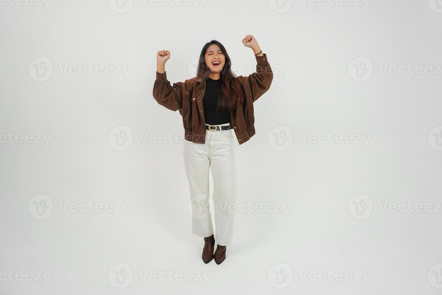 A happy young Asian woman wearing casual wear is posing to the camera with her hands open, expressing freedom and carefree photo