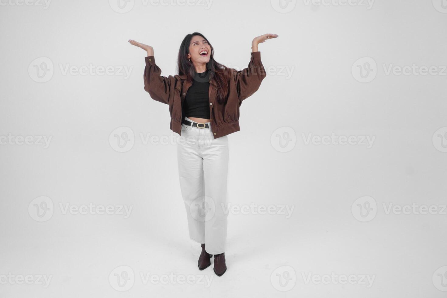 Happy Asian woman wearing casual clothes smiling while pointing up at a copy space, standing at isolated white background photo