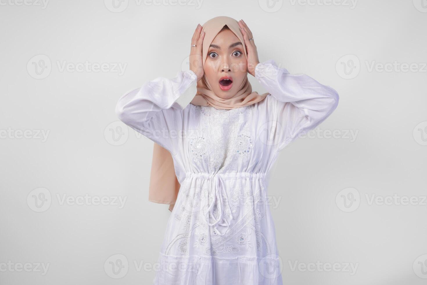 retrato de joven asiático musulmán mujer vistiendo blanco vestir y hijab con sorprendido expresión y boca amplio abierto después escuchando impactante Noticias terminado aislado blanco antecedentes foto