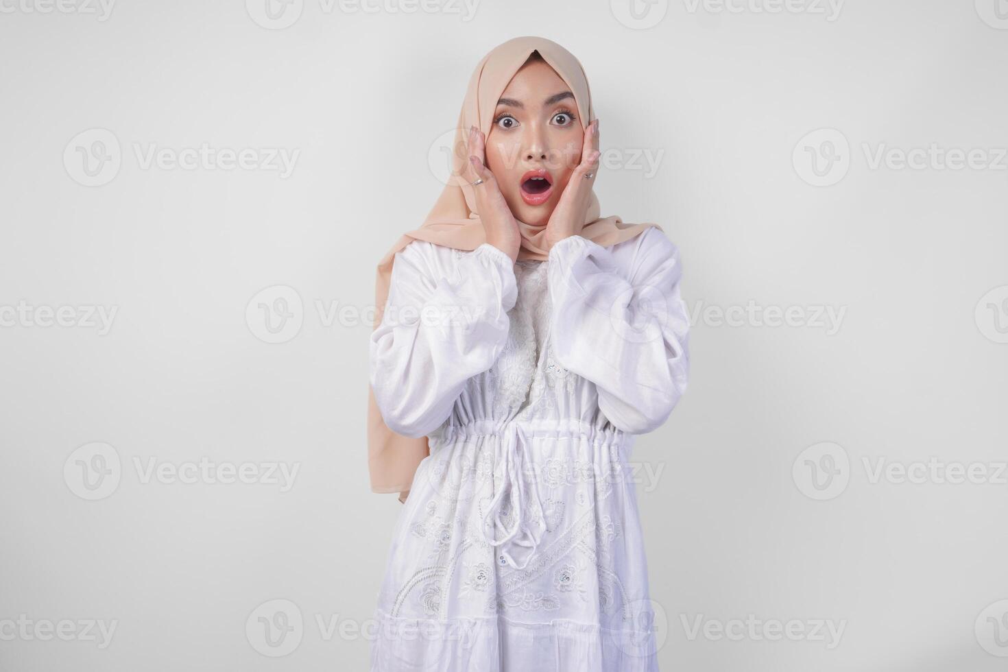 retrato de joven asiático musulmán mujer vistiendo blanco vestir y hijab con sorprendido expresión y boca amplio abierto después escuchando impactante Noticias terminado aislado blanco antecedentes foto