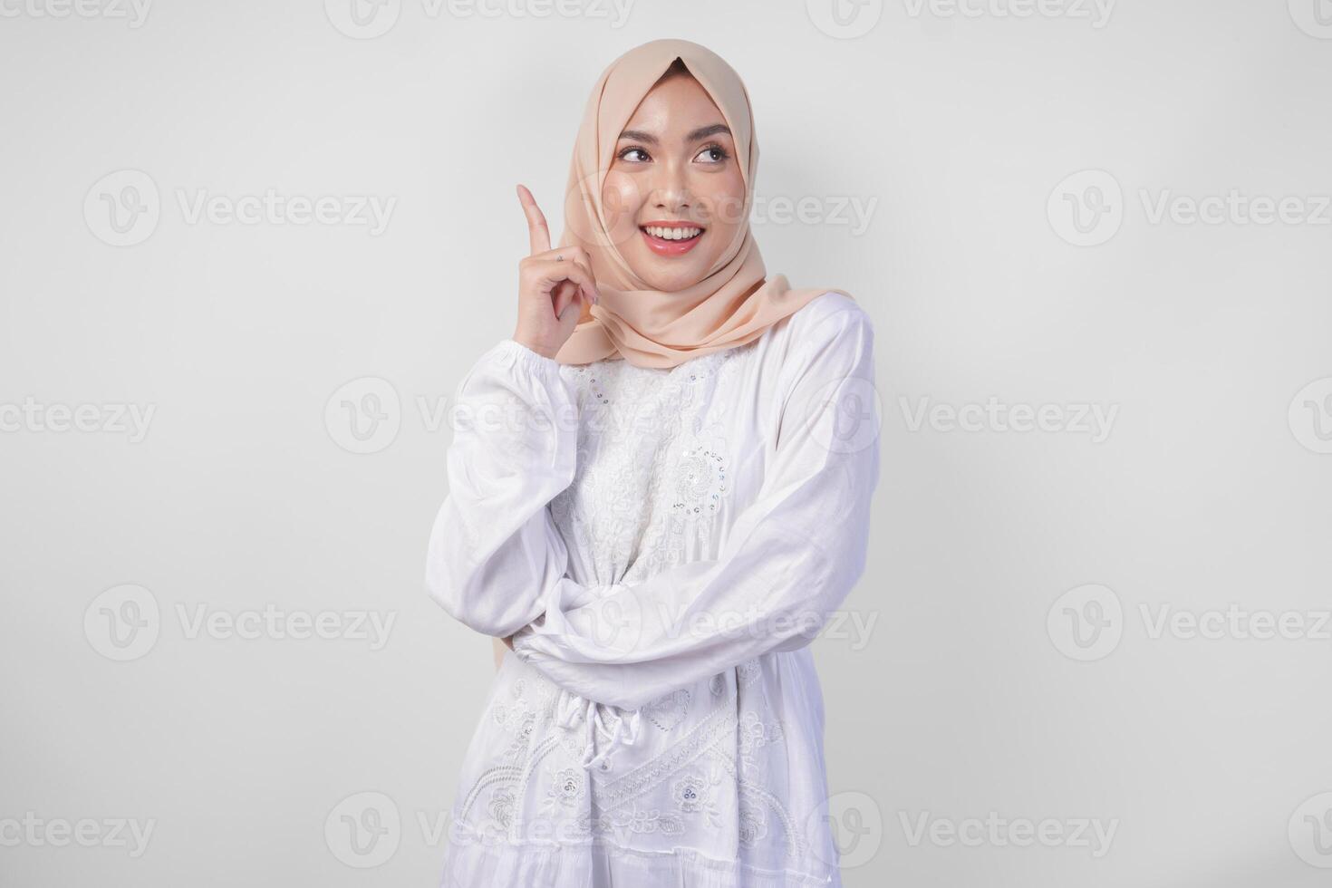 pensativo joven asiático musulmán mujer vistiendo blanco vestir y hijab pensando y hallazgo idea con contento expresión, aislado en blanco antecedentes foto