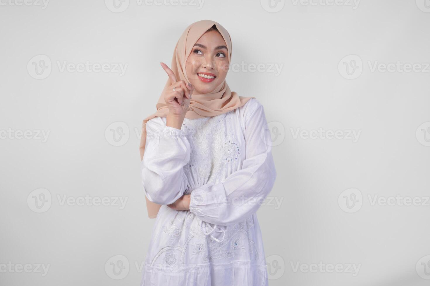 emocionado asiático mujer vistiendo hijab y blanco vestir señalando a el Copiar espacio en su Derecha lado, en pie terminado aislado blanco antecedentes. Ramadán y eid Mubarak anuncio concepto foto