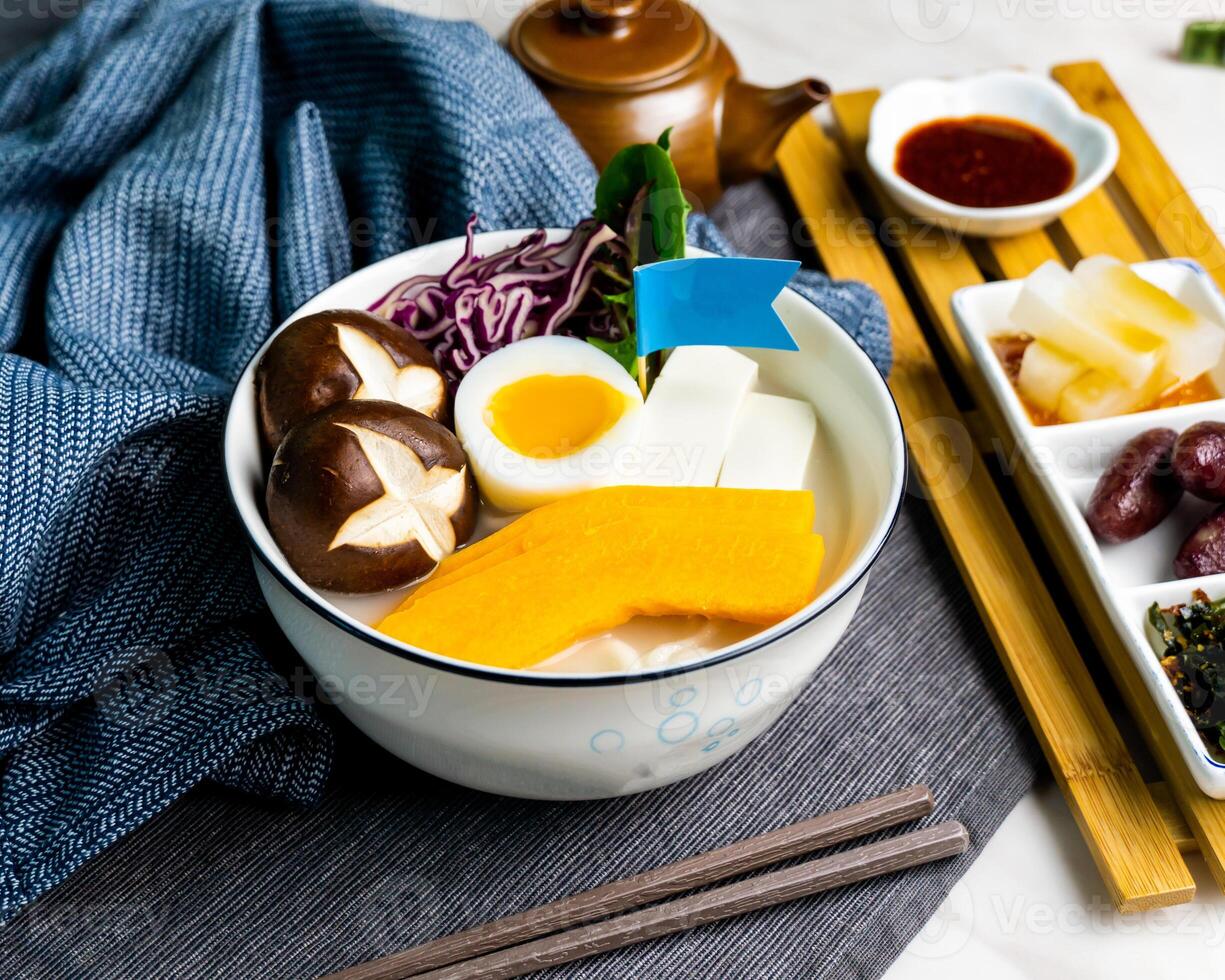 Fish Udon in Thick Fish Soup served in bowl with chopsticks and topping flag isolated on napkin side view of japanese food on table photo