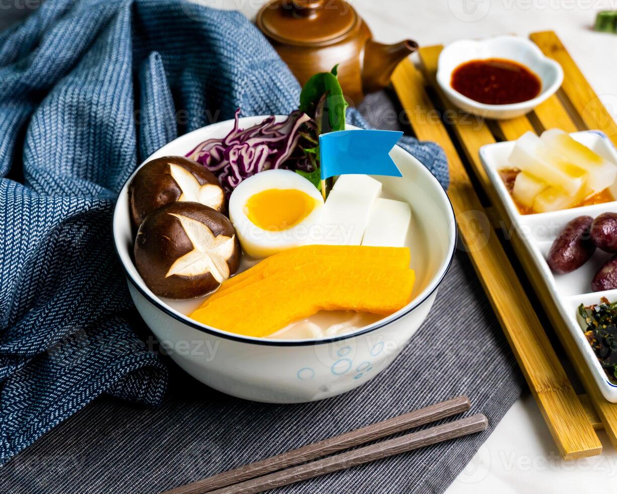 Fish Udon in Thick Fish Soup served in bowl with chopsticks and topping flag isolated on napkin side view of japanese food on table photo