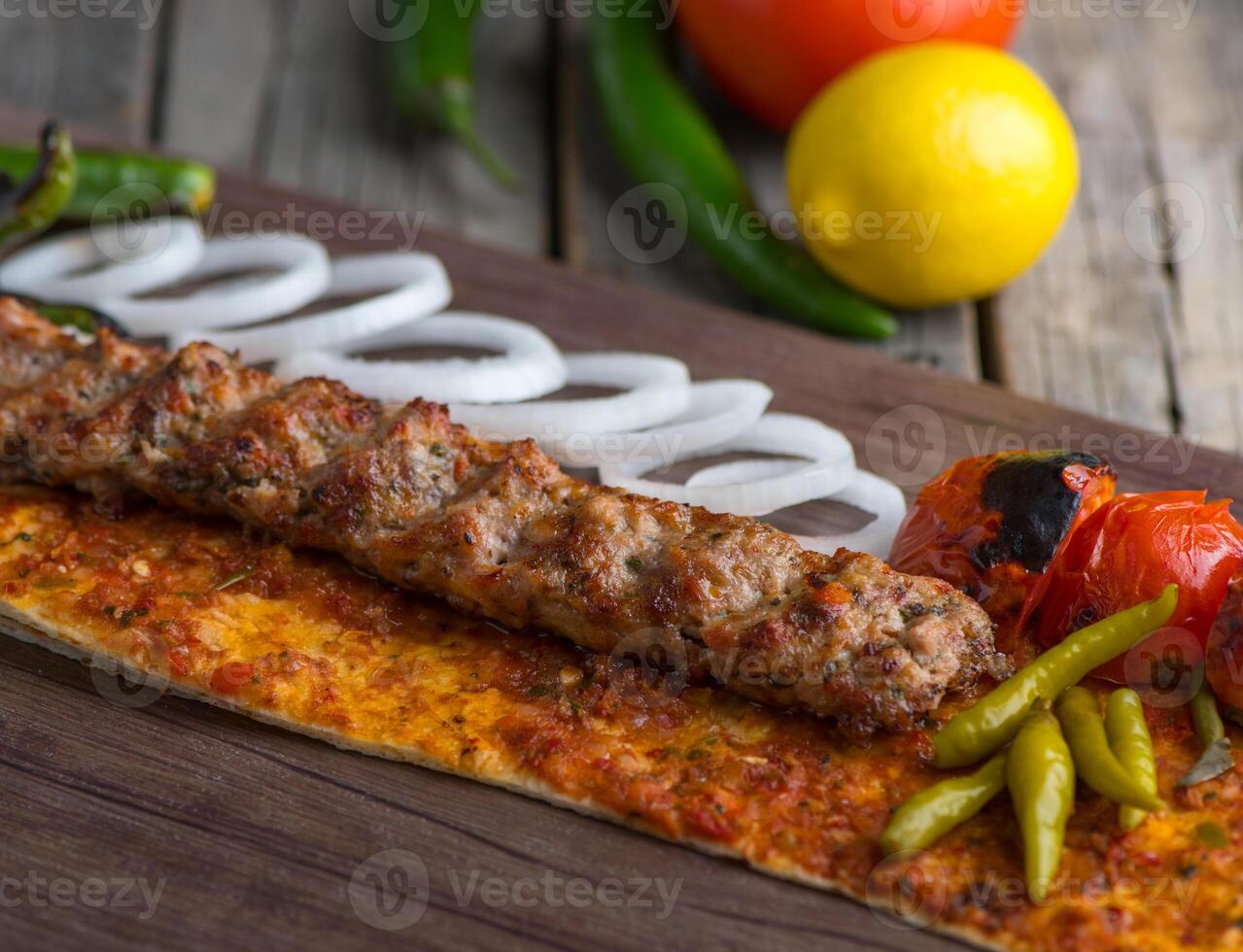 Chicken seekh kabab with onion ring, lime and tomato served in dish side view on wooden table background photo