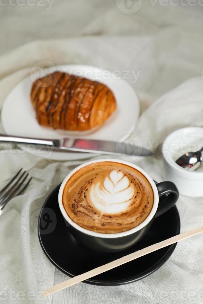 Hot Macchiato Coffee Latte Art served in cup with croissant, puff pastry, bread and knife isolated on napkin side view cafe breakfast photo