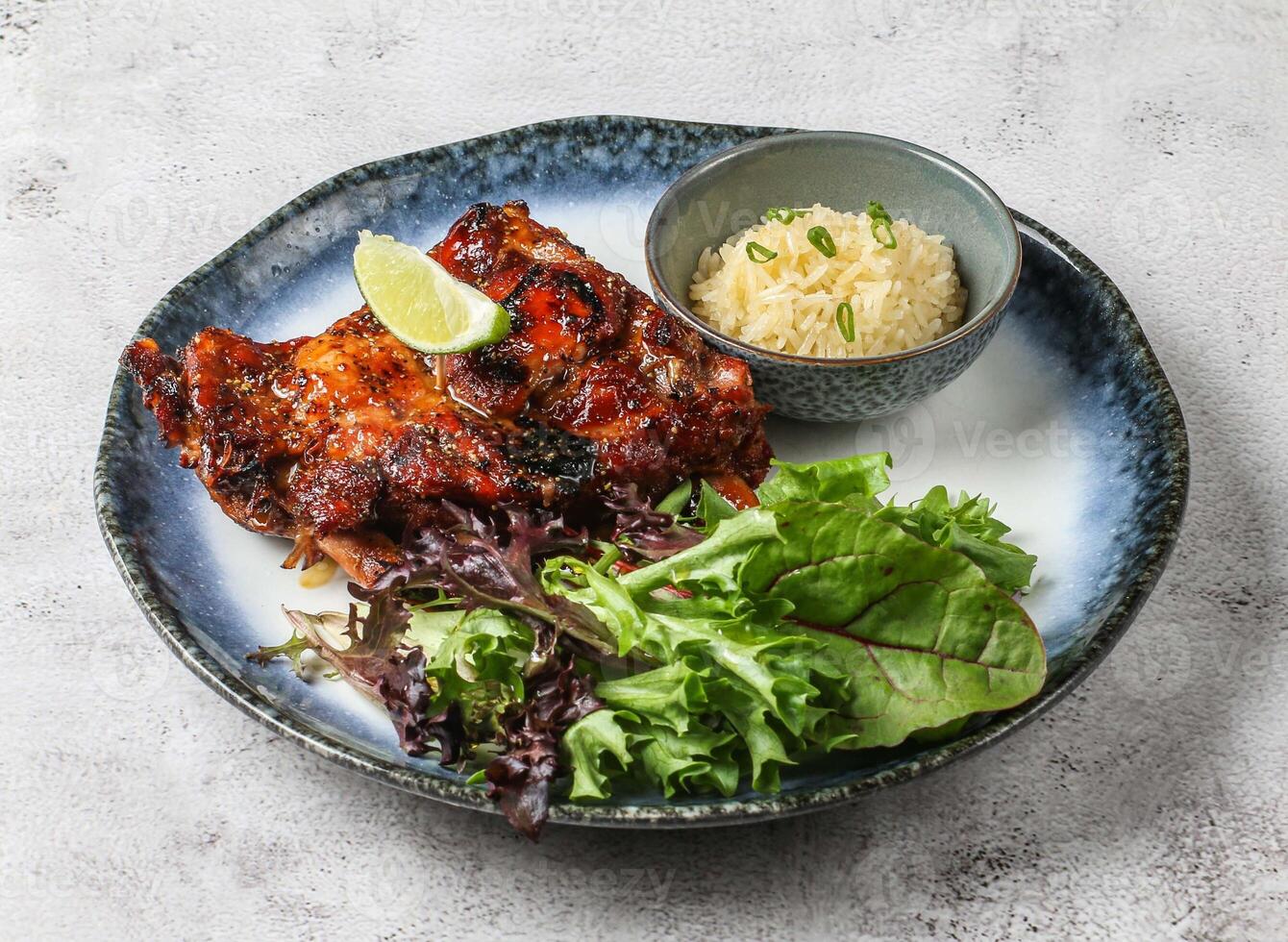chao ta grilled pork ribs with plai rice, lemon and green leaves served in dish isolated on grey background top view of singapore food photo