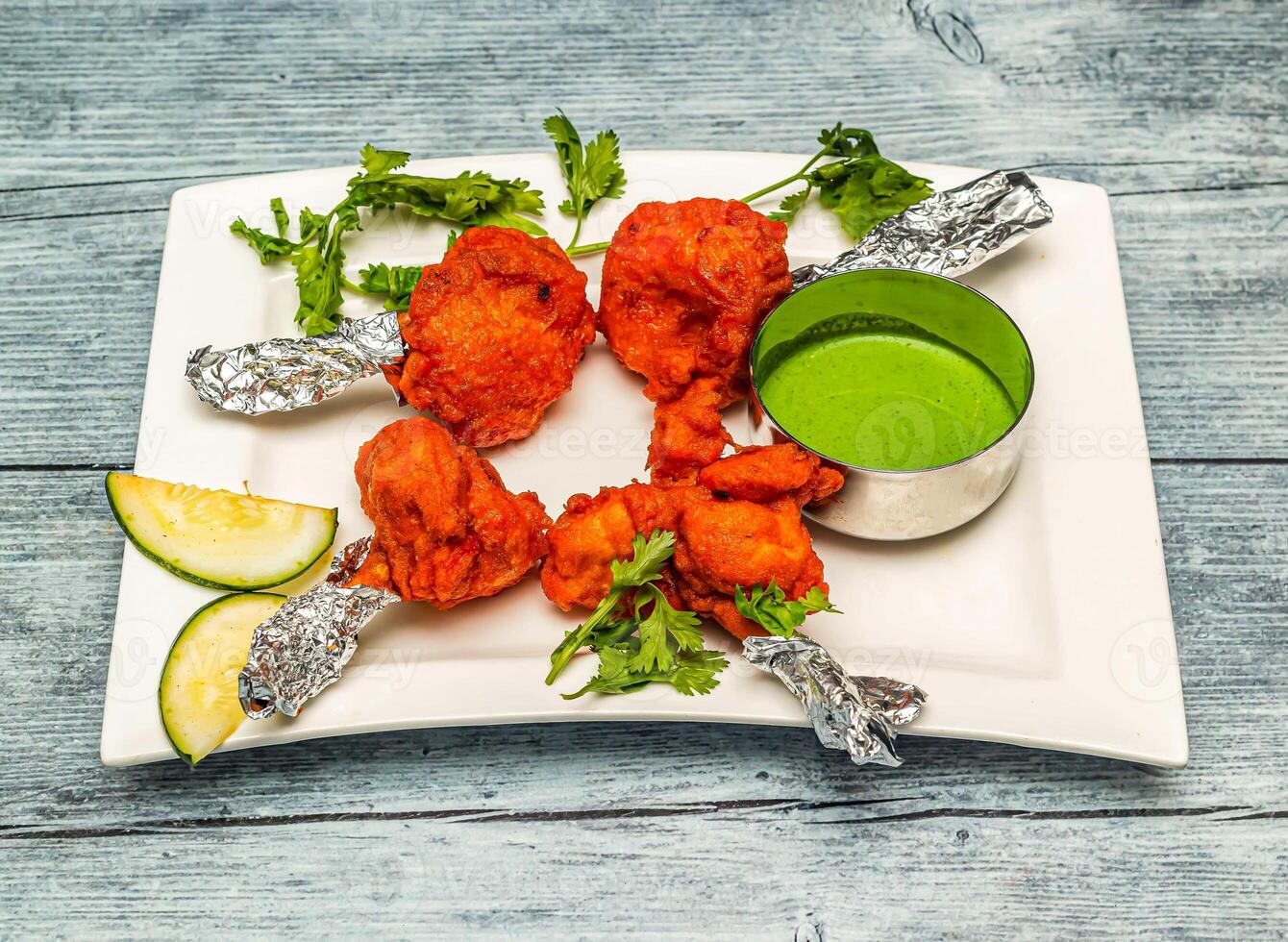 chicken lollipop or lollypop with chutney sauce served in dish isolated on wooden table top view of indian spicy food photo