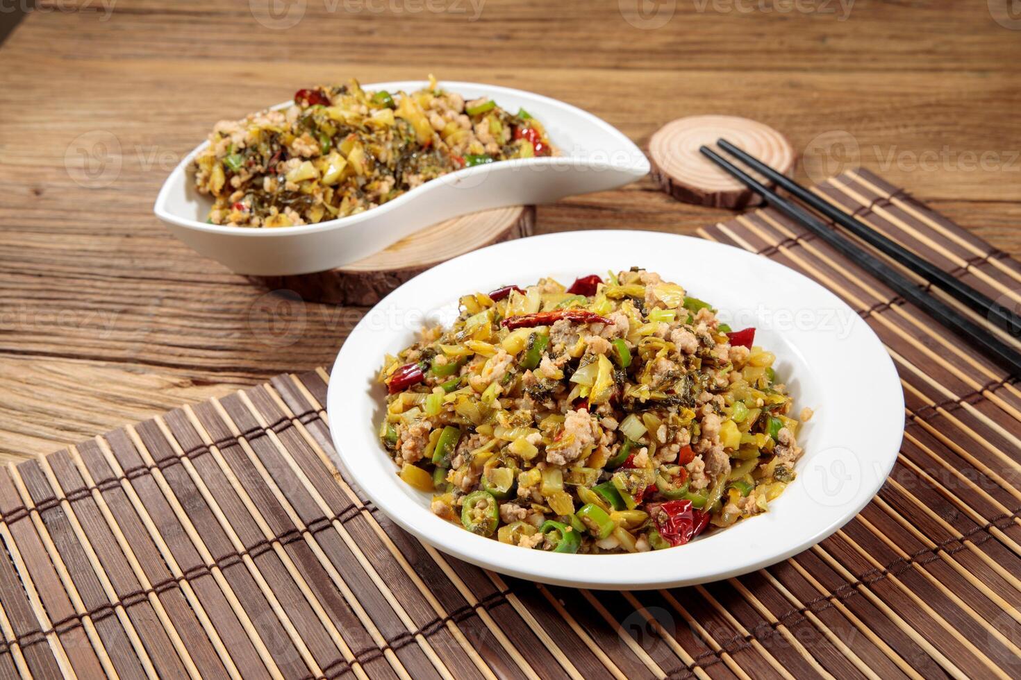 Stir-fried pork mince with sauerkraut with chopsticks served in dish isolated on mat top view on wooden table Hong Kong food photo