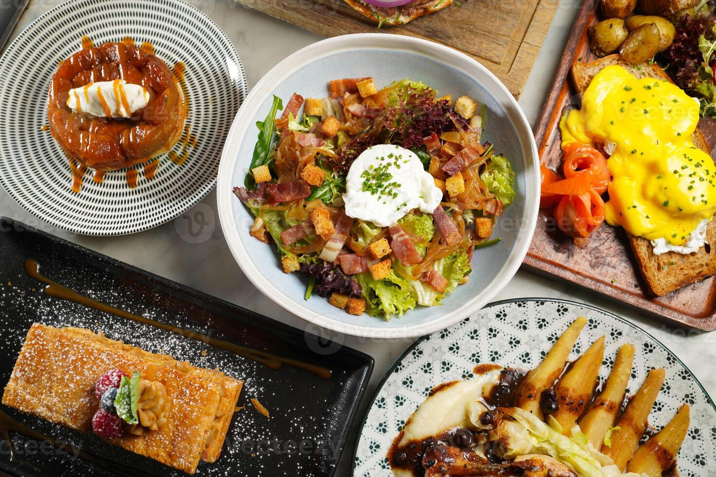 Tart tatin, Salade Lyonnaise, Bacon Et Poche, Millefeuille Praline, Eggs Provencal, Roasted Guinea Fowl Breast, Metro Cheese Burger, served in dish on marble background top view on hong kong food photo