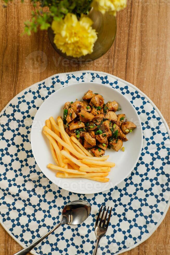 Fried Calamari with french fries, spoon and fork served in dish isolated on table top view of fastfood appetizer photo