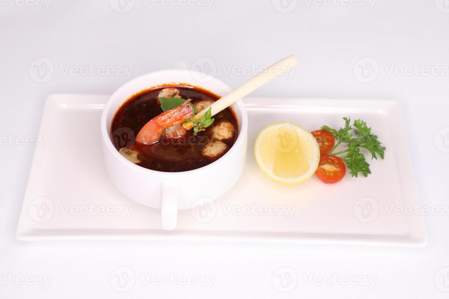 TOM YUM PRAWN SOUP with lemon, tomato and spoon served in dish isolated on background side view of arab food photo