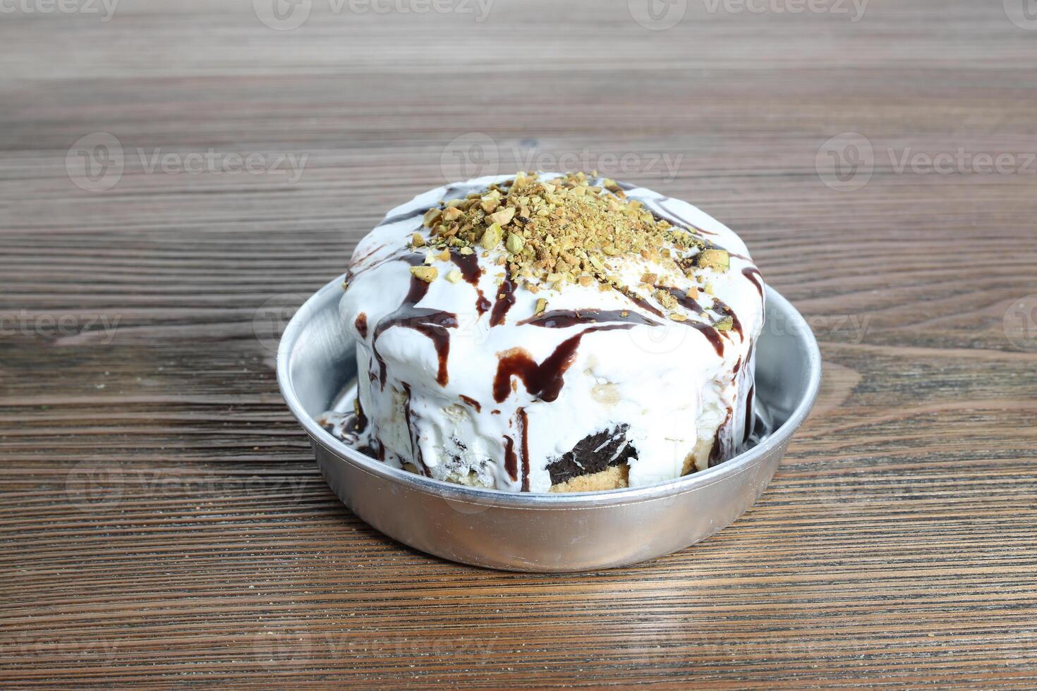 Arabic Sweetness bomb with chocolate, ice cream and pistachio topping served in dish isolated on table side view of arabic dessert food photo